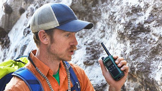 Man rock climbing using a handheld radio