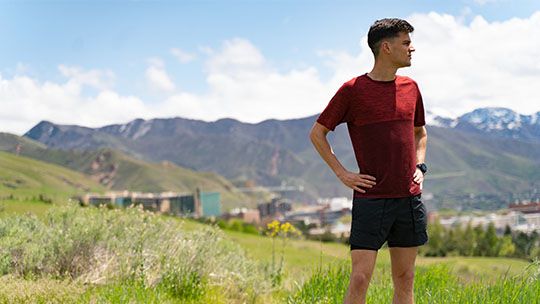 Man standing on side of hill with mountains in the background