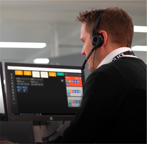 Image of white male worker wearing headset and looking at computer screen