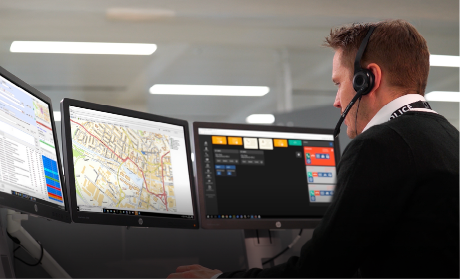 Image of white male worker wearing headset and looking at computer screen